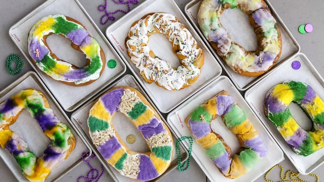 An array of purple, yellow, and green decorated king cakes in their boxes waiting to be eaten!